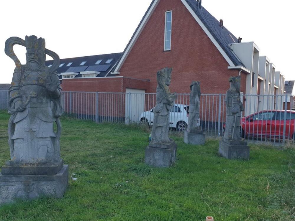 Een rij stenen Chinese beelden in het gras in Colijnsplaat